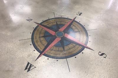 Blue, red, and gold colored compass rose installed on a polished concrete floor using 3.4 mil vinyl stencil and Ameripolish dye.