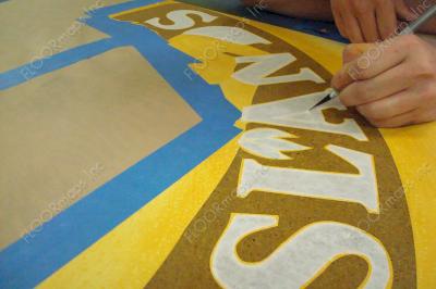 Close up of masking to cover all gold text of Hawaiian Islands to protect them from the red coloring that is next to be applied.