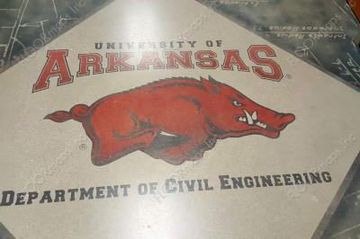 Front view of a black and red razorback logo with University of Arkansas Department of Civil Engineering Text and a blue engineering textual background.