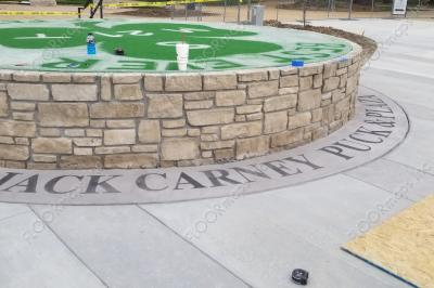 Jack Carney Puck and Plaza text installed with Colored cementitious Overlay wraps around a center island outside in Chicago.