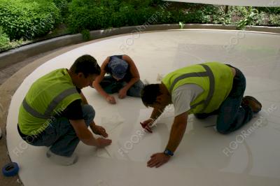 Crew installing dragon design on concrete overlay using 2 mil HighTack vinyl stencil